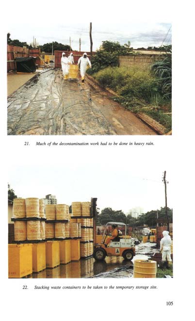 Trabalhadores com equipamento de proteção individual realizando descontaminação de solo contaminado por césio-137 durante chuva forte em Goiânia, com lona plástica cobrindo a área de trabalho