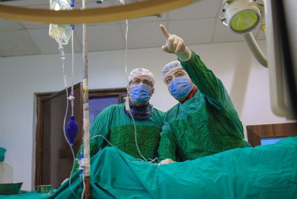 Equipe medica realizando procedimento guiado por imagem em sala de radiologia intervencionista