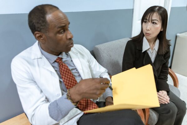 Médico explicando um laudo radiológico impresso a uma paciente no consultório