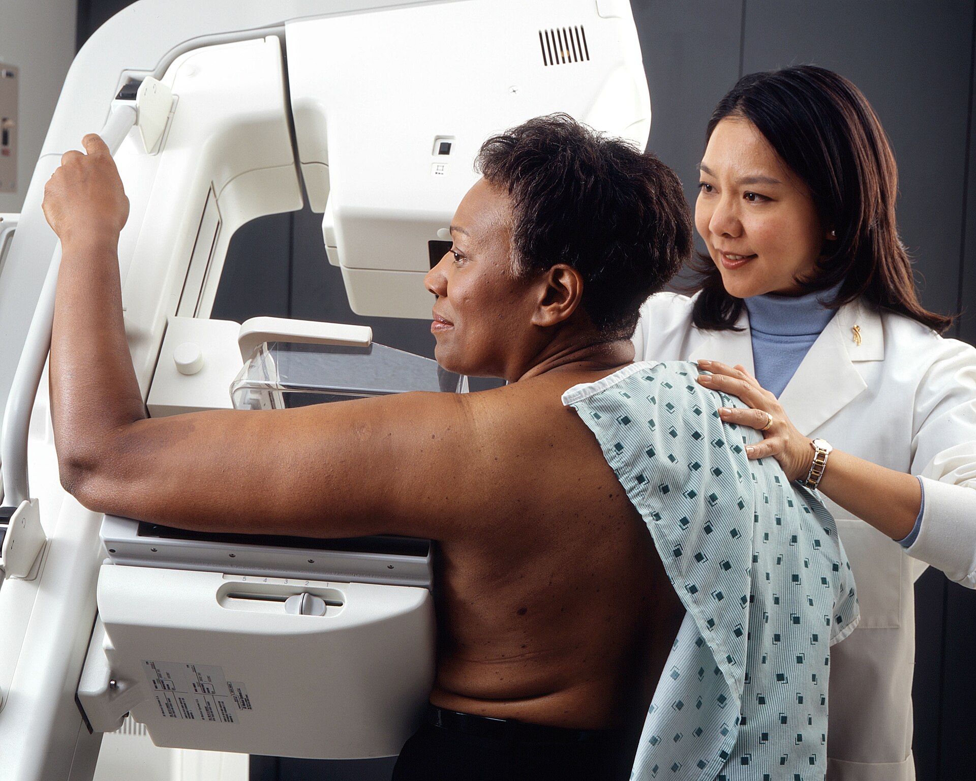 Woman undergoing screening mammography assisted by a health professional in an imaging service