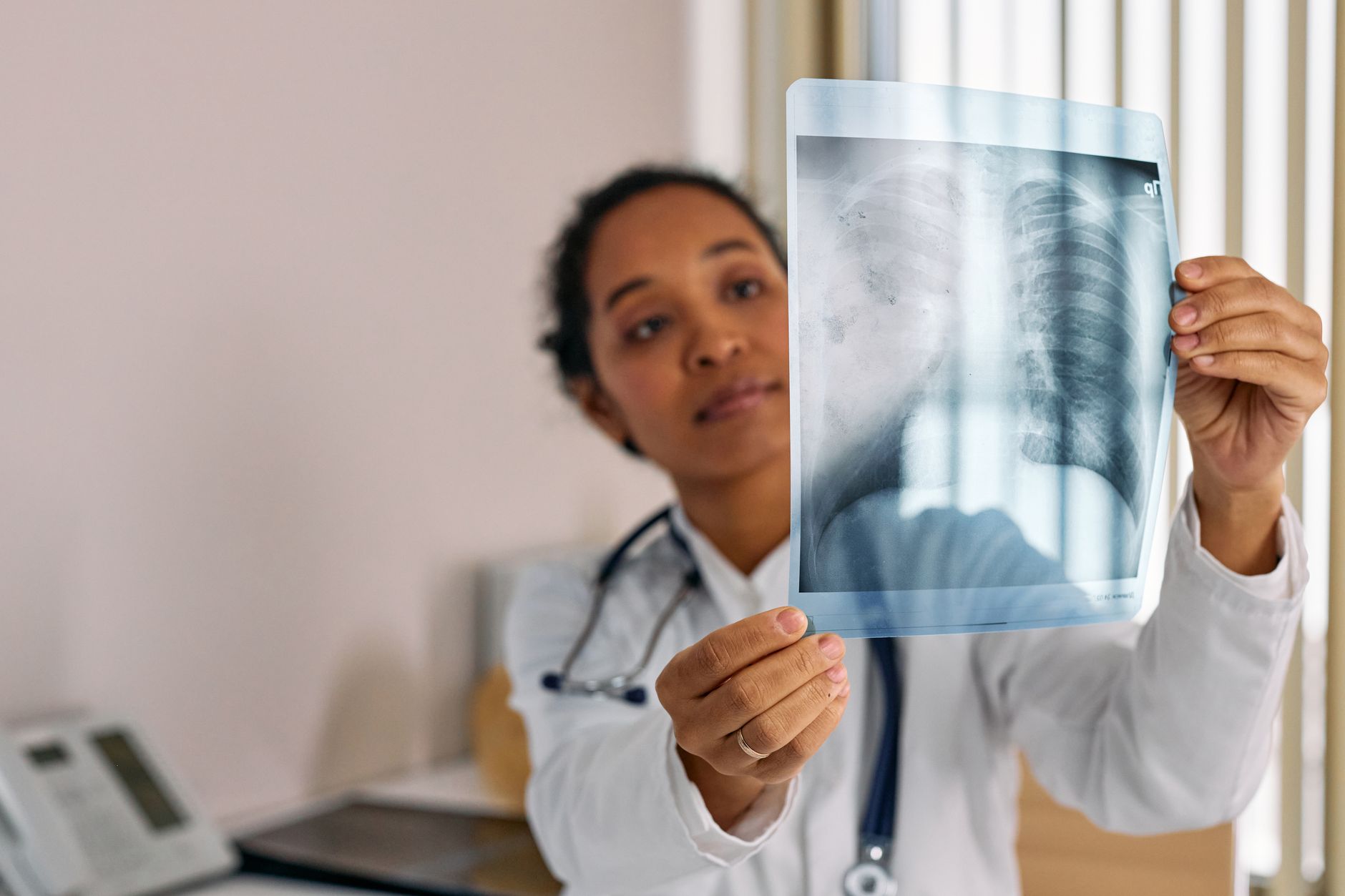Physician holding a chest radiograph up to the light, assessing the lung fields and apices
