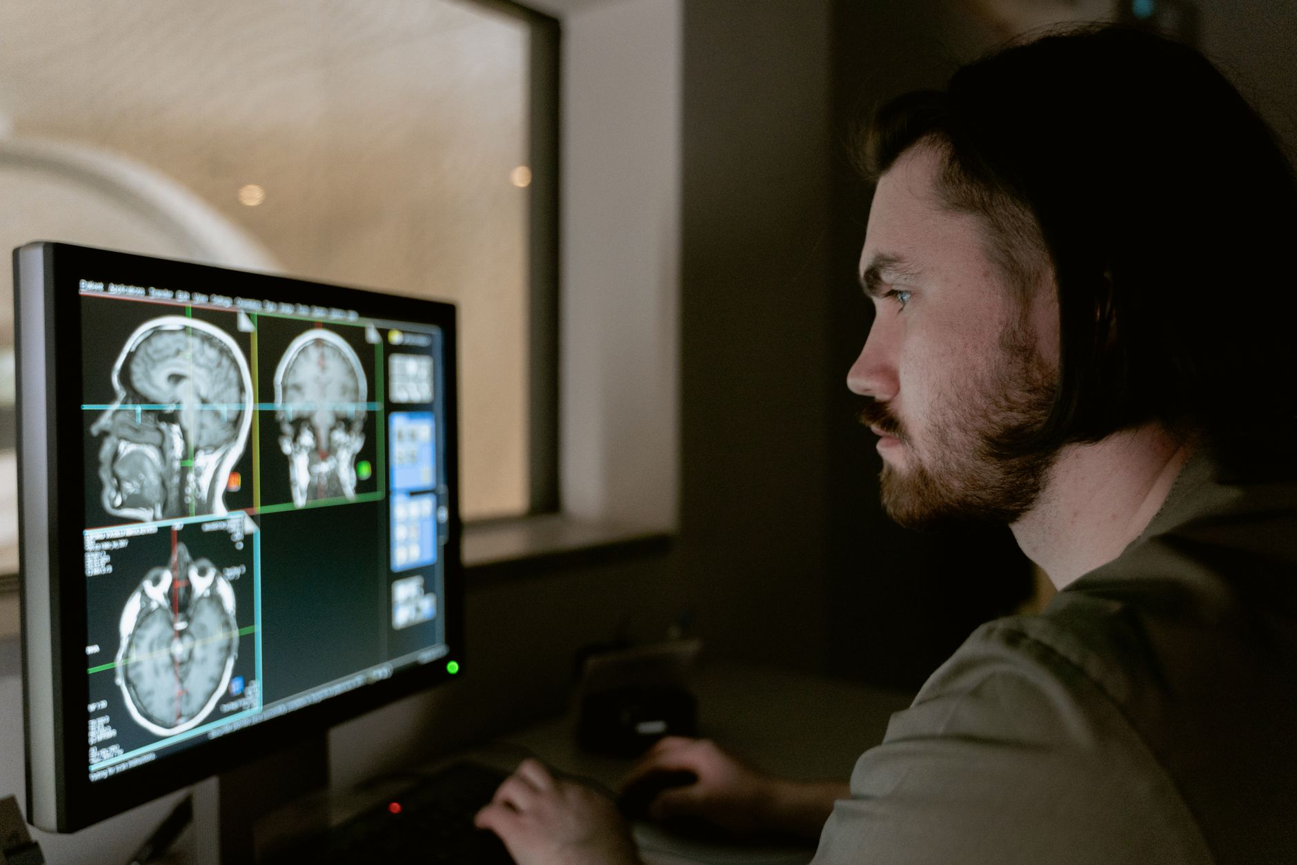 Clinician reviewing sagittal, coronal and axial brain imaging slices on a workstation monitor