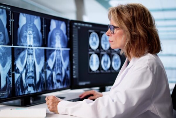 Radiologista revisando exame de ressonancia magnetica de corpo inteiro em multiplos monitores