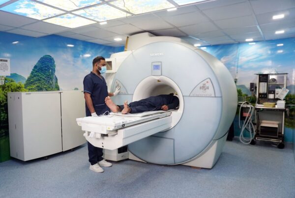 Tecnólogo posiciona paciente em aparelho de ressonância magnética em centro de diagnóstico por imagem