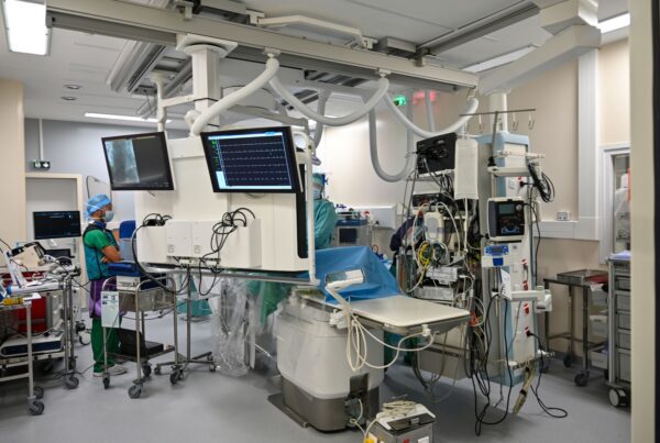 Sala de angiografia com arco em C e monitor de fluoroscopia, ambiente típico de embolização hepática