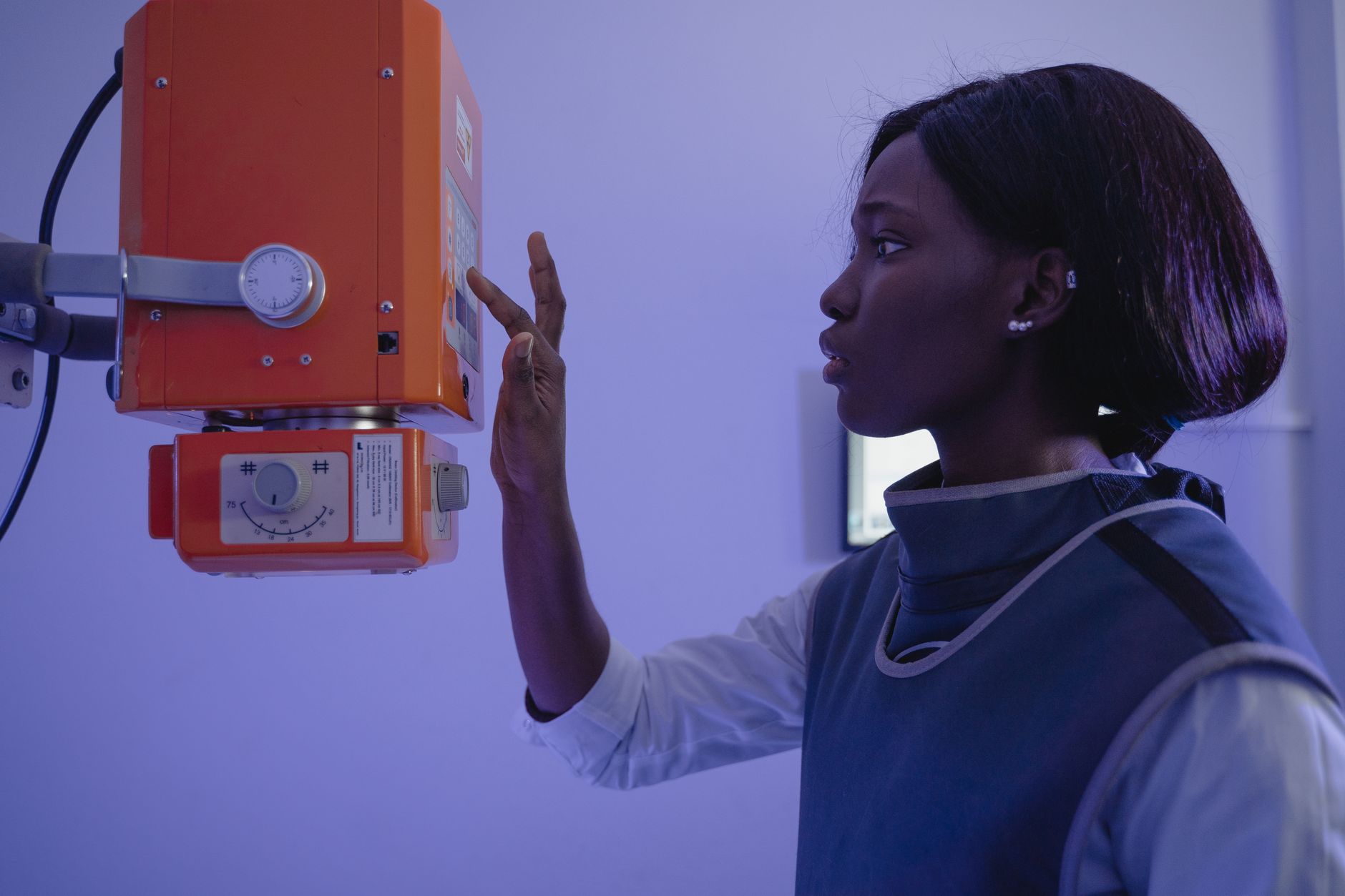 Healthcare worker operating X-ray equipment in a clinical setting, illustrating population screening exams